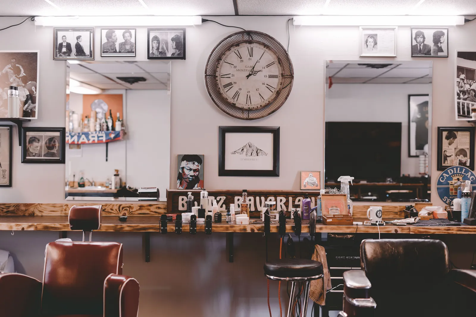 Interior de uma barbearia com cadeiras de couro, espelhos e um relógio de parede.